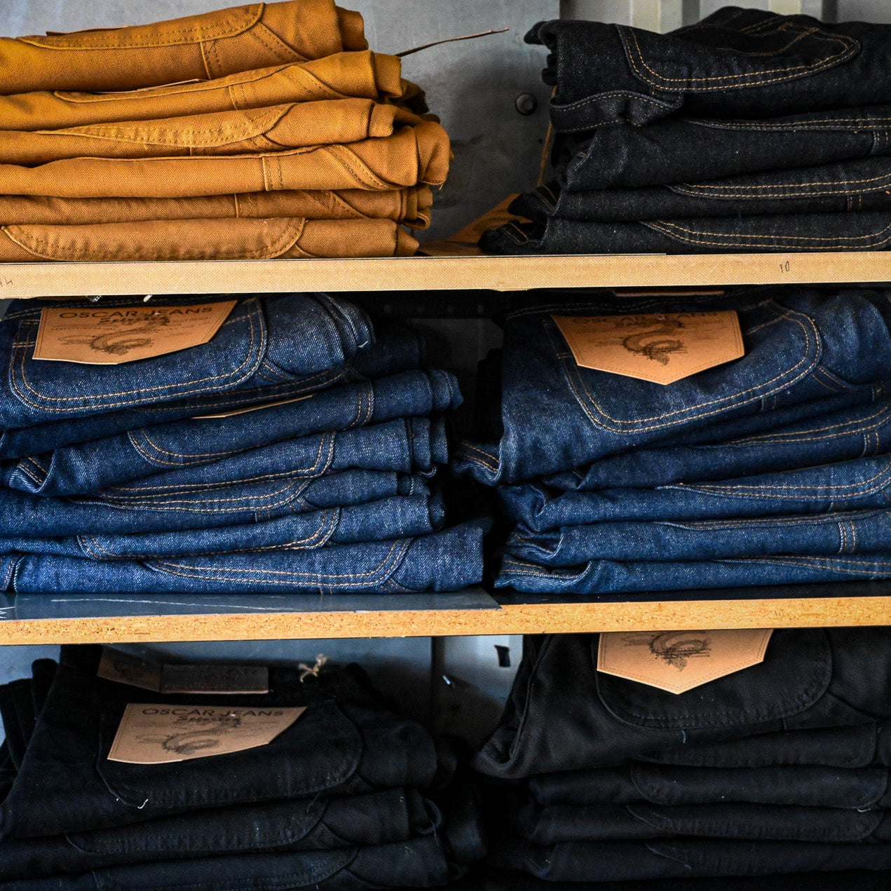 Stacks of folded jeans on shelves in a storage area