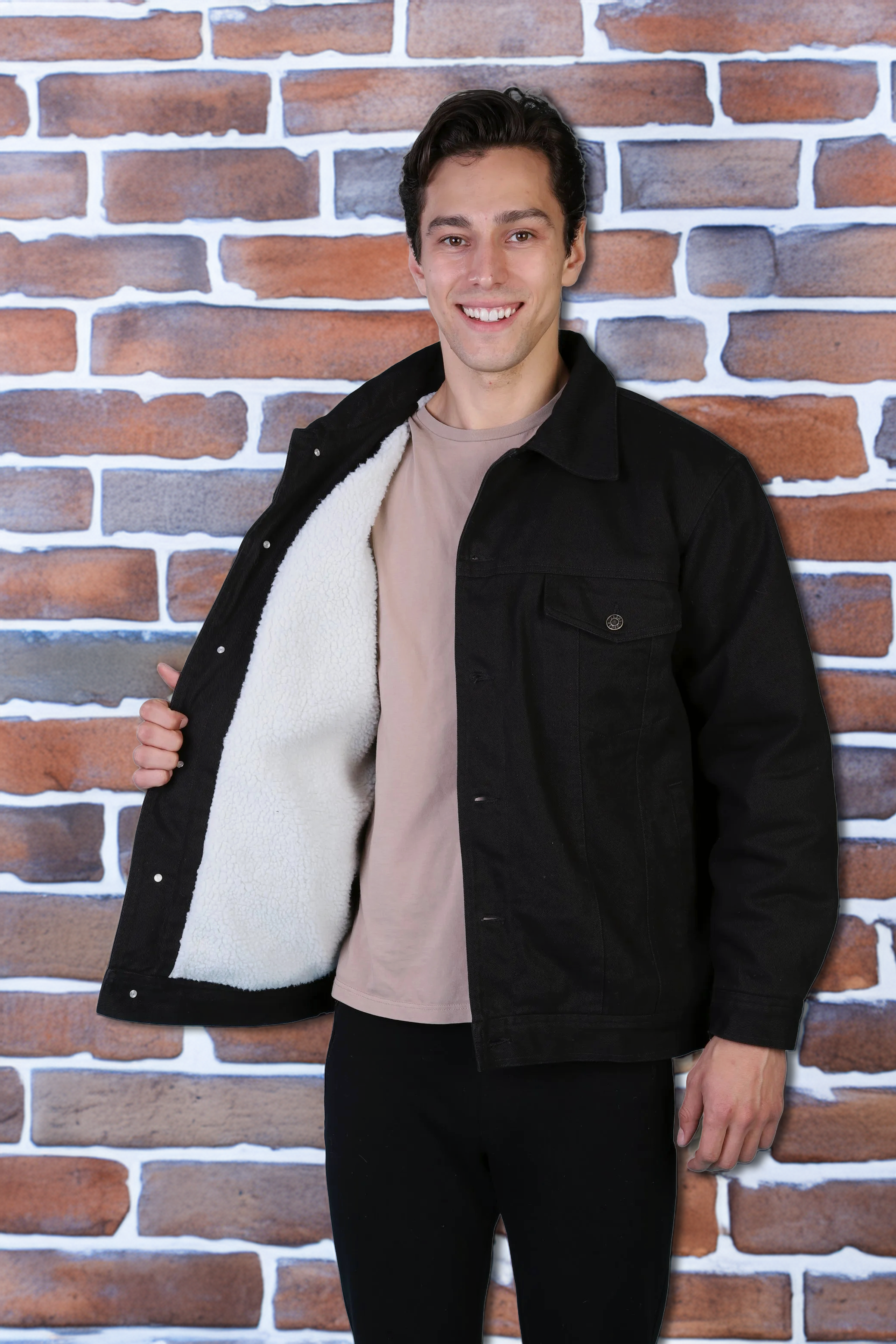 Man in a black Oscar sherpa-lined corduroy trucker jacket against a brick wall