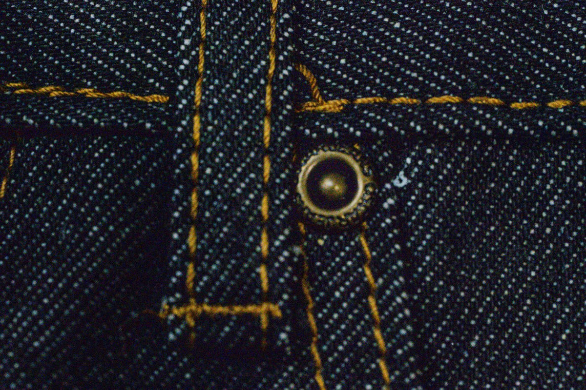 Brass rivet and gold chainstitch on indigo denim